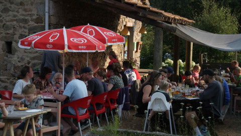 Buiten eten bij Domaine la Chabanne - Safaritenten Auvergne-Rhône-Alpes met families onder rode parasols.