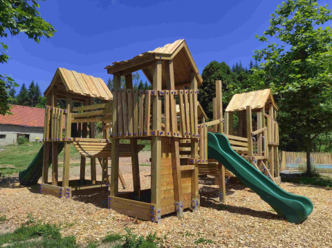 Playground with wooden climbing frames and green slide at Domaine la Chabanne - Safaritenten Auvergne-Rhône-Alpes.