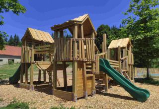 Speeltuin met houten constructies en groene glijbaan bij Domaine la Chabanne - Safaritenten Auvergne-Rhône-Alpes.