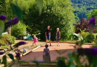 Familie hygger sig ved Domaine la Chabanne glamping i Auvergne-Rhône-Alpes, omgivet af frodige grønne træer.