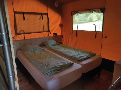 Vue intérieure d’un hébergement glamping avec deux lits simples au Domaine la Chabanne, Auvergne-Rhône-Alpes.