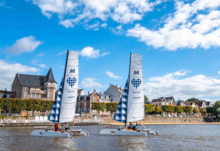 Twee catamarans varen op een rivier voor historische gebouwen nabij Domaine la Chabanne, Auvergne-Rhône-Alpes.
