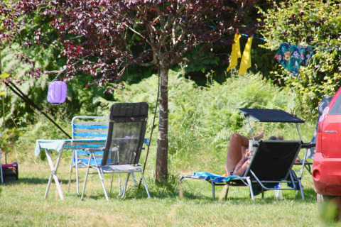 Outdoor relaxation at Domaine la Chabanne Safaritenten, with camping chairs and sunbed under a tree, summer vibe.