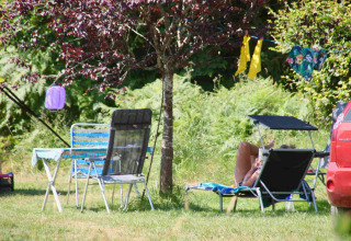 Détente en plein air au Domaine la Chabanne Safaritenten, avec chaises et transat à l’ombre d’un arbre, ambiance estivale.