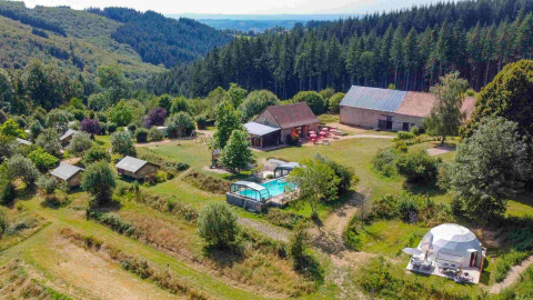 Vista aerea del glamping Domaine la Chabanne con tende safari, piscina e boschi in Auvergne-Rhône-Alpes.