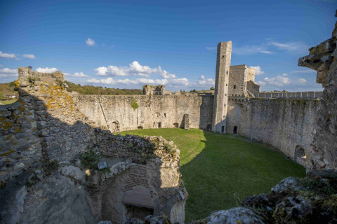 View of ancient castle walls and grassy courtyard at Domaine la Chabanne - Safaritenten Auvergne-Rhône-Alpes.