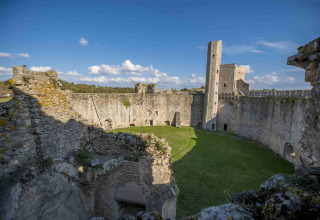 View of ancient castle walls and grassy courtyard at Domaine la Chabanne - Safaritenten Auvergne-Rhône-Alpes.