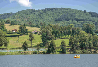 Vista de Domaine la Chabanne - Safaritenten Auvergne-Rhône-Alpes con lago, colinas y vegetación.