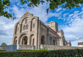 Grande église en pierre sous un ciel bleu près du Domaine la Chabanne - Safaritenten Auvergne-Rhône-Alpes camping.