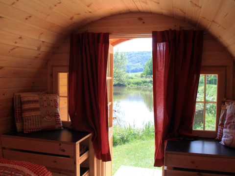 Innenansicht einer Glamping-Unterkunft mit roten Vorhängen und Seeblick, Camping Naturama Beilngries.