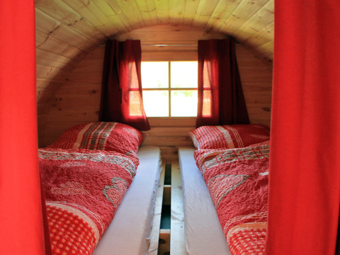 Twee eenpersoonsbedden met rood beddengoed in een wijnvat bij Camping Naturama Beilngries - Wijnvaten in Beieren.
