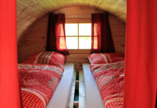 Dos camas individuales con sábanas rojas en un alojamiento glamping de Camping Naturama Beilngries en Baviera.