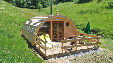 Alojamiento glamping Vollmershof - Lodge Zwarte Woud en colinas verdes, con terraza de madera y tumbonas.
