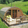 Glamping accommodation Vollmershof - Lodge Zwarte Woud set in lush green hills with wooden deck and garden chairs.