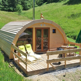 Glampingverblijf Vollmershof - Lodge Zwarte Woud in het groen, houten terras met ligstoelen en tafeltje.
