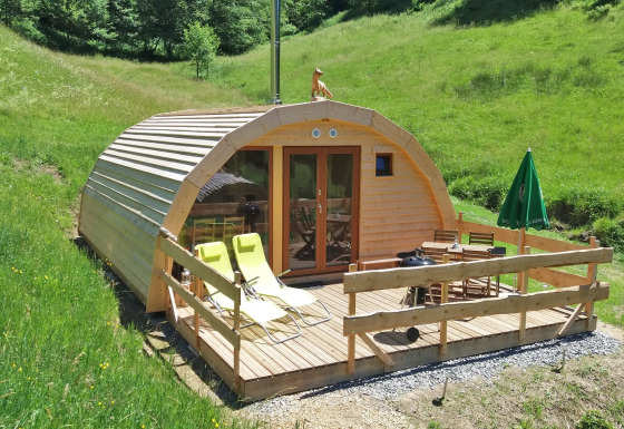Glampingverblijf Vollmershof - Lodge Zwarte Woud in het groen, houten terras met ligstoelen en tafeltje.