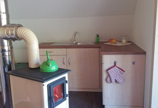 Cucina interna a Vollmershof - Lodge Zwarte Woud glamping con stufa a legna, lavello e arredi moderni.