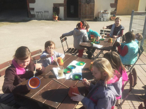 Niños pintan macetas al aire libre en Vollmershof - Lodge Zwarte Woud, sitio de glamping o camping.