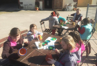 Bambini dipingono vasi all'aperto al Vollmershof - Lodge Zwarte Woud, area di glamping o campeggio.