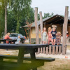Children play in front of a safari tent at Camping de Pallegarste, Overijssel, as adults relax on picnic tables.