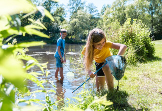 To børn fanger fisk i en sø ved Camping de Pallegarste - Safaritenten Overijssel på en solrig dag.