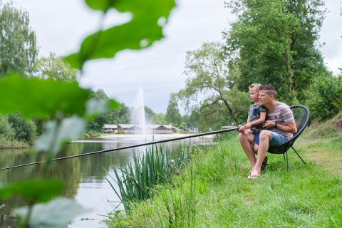 Padre e figlio pescano sul lago al Camping de Pallegarste - Safaritenten Overijssel, immersi nella natura.