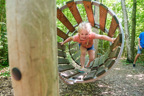 Kind speelt in een houten tunnel op Camping de Pallegarste - Safaritenten Overijssel in Nederland.