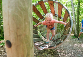 Kind speelt in een houten tunnel op Camping de Pallegarste - Safaritenten Overijssel in Nederland.