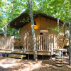 Modern safari tent glamping accommodation at Chianti Glamping Resort, Tuscany, surrounded by green trees.