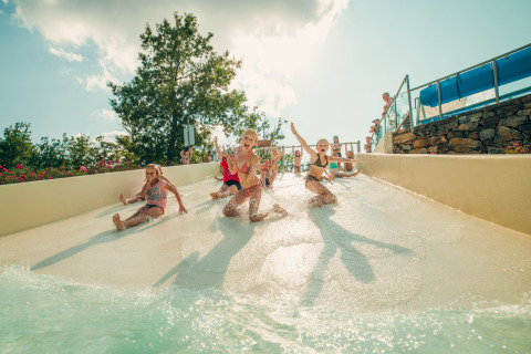 Kinderen glijden lachend van een waterglijbaan op Chianti Glamping Resort in het zonnige Toscane.