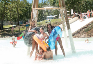Kinderen spelen met opblaasbare banden onder een waterval in Chianti Glamping Resort, Toscane, Italië.