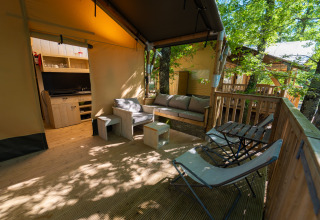 Terrasse eines Safarizelts im Chianti Glamping Resort mit gemütlichen Sitzgelegenheiten, umgeben von Natur.