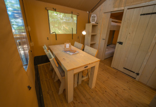 Eethoek met houten tafel en stoelen in een safaritent bij Chianti Glamping Resort in Toscane, Italië.