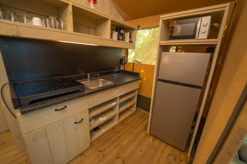 Cocina moderna con nevera, microondas, fregadero y placa en Chianti Glamping Resort en la Toscana, Italia.