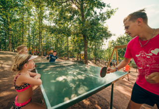 Bambini giocano a ping pong all'aperto al Chianti Glamping Resort, immersi nella natura e negli alberi.