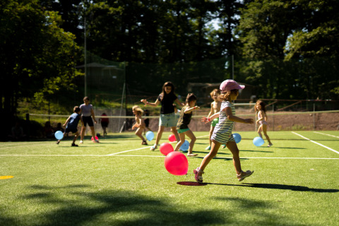 Kinderen spelen met ballonnen op het gras bij Vacanze col Cuore: Chianti Glamping Resort – Safaritenten Toscane.