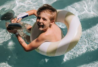 Dreng leger i pool med badering på Recreatiepark de Achterste Hoef - Safaritenten Brabant, campingglæde.