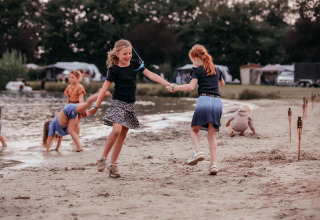 Children playing on the sandy beach at Recreatiepark de Achterste Hoef - Safaritenten Brabant campsite.