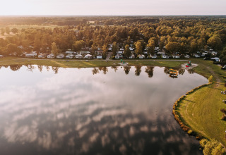Aerial view of Recreatiepark de Achterste Hoef campsite with a lake and glamping tents in Brabant, Netherlands.
