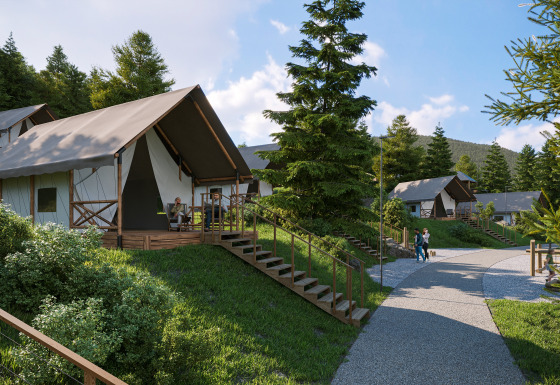 Glamping Village Kötschach - Safaritenten Karinthië: modern safari tents on grassy hills amid pine trees and mountains.