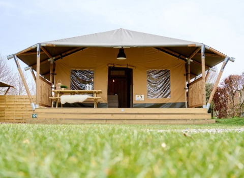 Hébergement glamping au Trixi Ferienpark en Saxe, tente safari avec terrasse, table de pique-nique et pelouse.