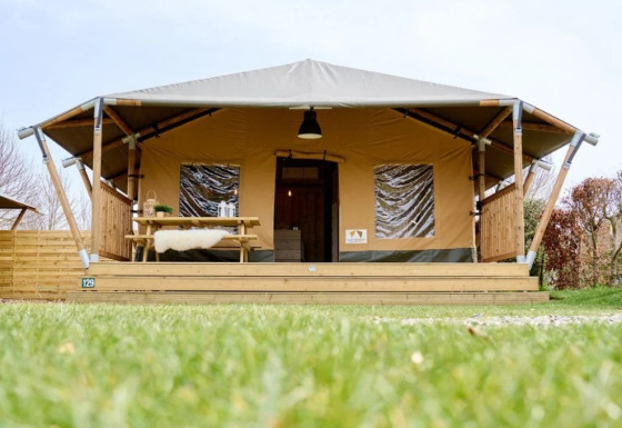 Glampingverblijf in Trixi Ferienpark, Saksen: safaritent met veranda, picknicktafel en uitzicht op gras.