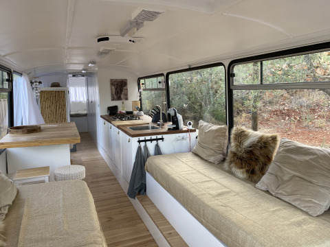 Interior of Algarve Olive Tree Lodge glamping bus with a cozy kitchen, seating area and large windows to nature.