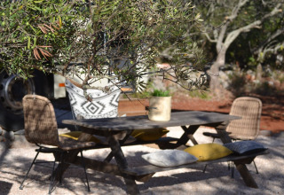 Tavolo da picnic all’aperto con sedie in vimini e cuscini al glamping Algarve Olive Tree Lodge in Portogallo.