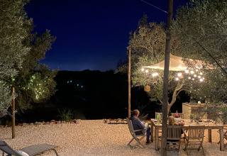 Zona de comedor exterior junto a luces y árboles en la noche en Algarve Olive Tree Lodge glamping.