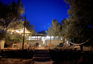 Charming glamping site with vintage school bus, hammock, and string lights at Algarve Olive Tree Lodge.