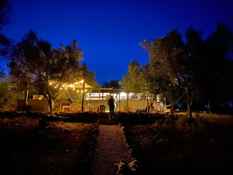 A lit glamping site at Algarve Olive Tree Lodge featuring a hippie schoolbus under the night sky.
