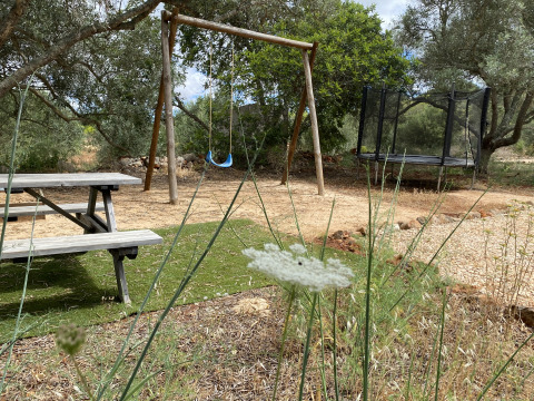 Area giochi all'aperto con altalena, trampolino e tavolo da picnic presso Algarve Olive Tree Lodge glamping.