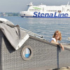 Woman enjoying glamping in a beach hut at Kiel Fjord, with a Stena Line ferry in the background.
