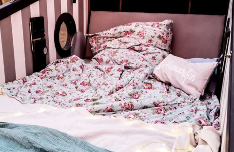 Hébergement glamping à Kiel avec literie florale et coussins, installé dans un fauteuil de plage typique.